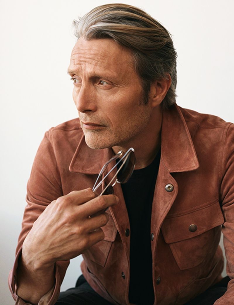 Actor Mads Mikkelsen sports a Tom Ford slim-fit suede jacket and t-shirt with Ralph Lauren Purple Label suit trousers and Barton Perreira sunglasses.