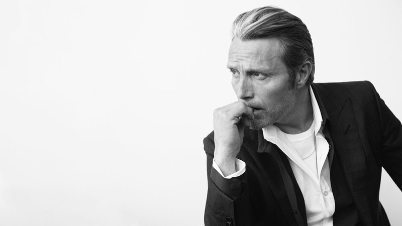 Mads Mikkelsen dons a Tom Ford t-shirt, shirt, and suit jacket with a black Berluti shirt.