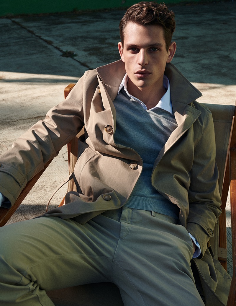 Pau Ramis dons a Massimo Dutti trench with a v-neck sweater, shirt, and chinos.