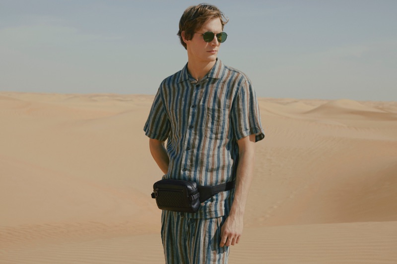 Small Bags: Felix Gesnouin wears a striped camp-collar linen shirt and trousers by Monitaly with a Bottega Veneta leather belt bag and Oliver Peoples sunglasses.