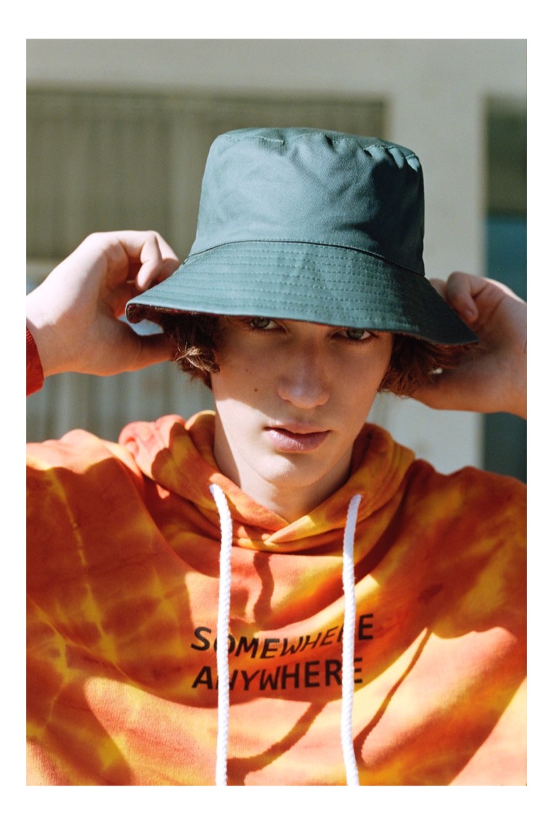 Channeling nineties style, Niks Gerbasevskis wears a tie-dye hoodie and bucket hat by Pull & Bear.