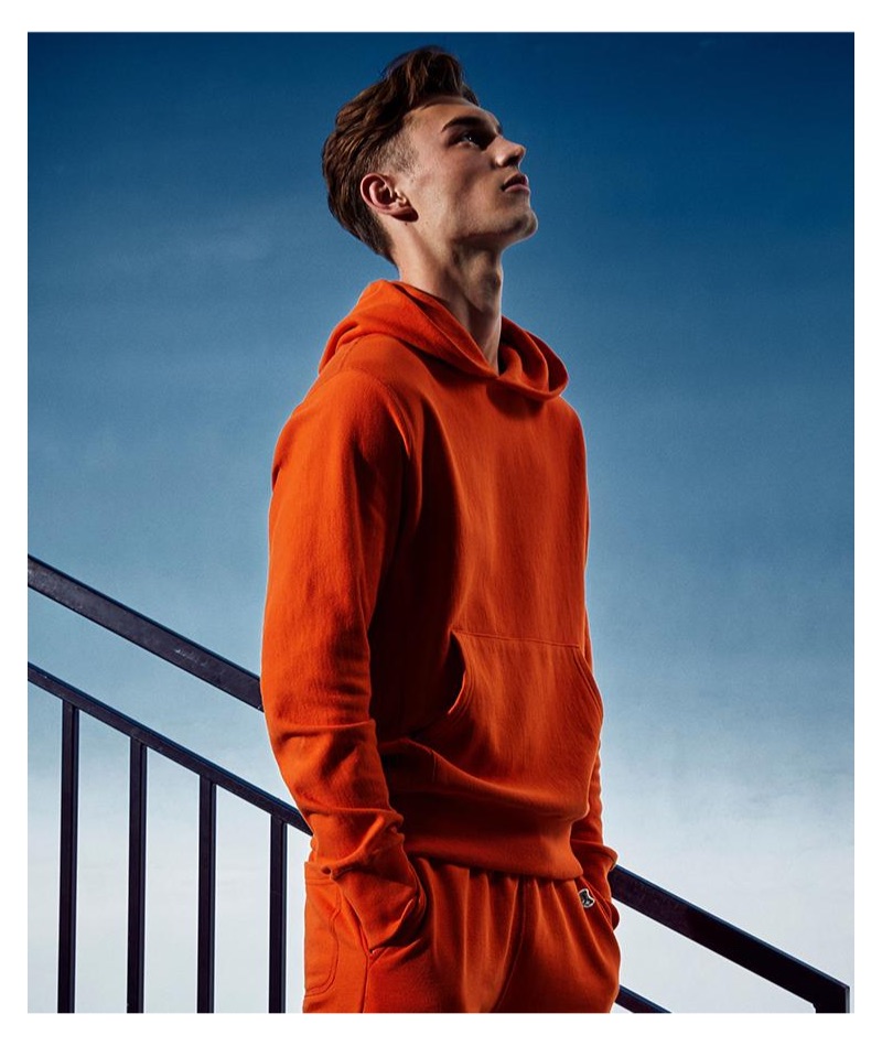 Kit Butler sports an orange Todd Snyder + Champion terry hoodie and jogger sweatpants.