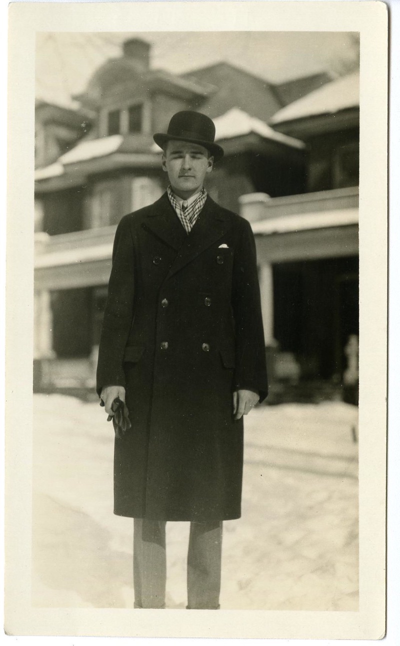 Photographed in the 1920s, a slender man poses in a double-breasted coat and bowler hat.
