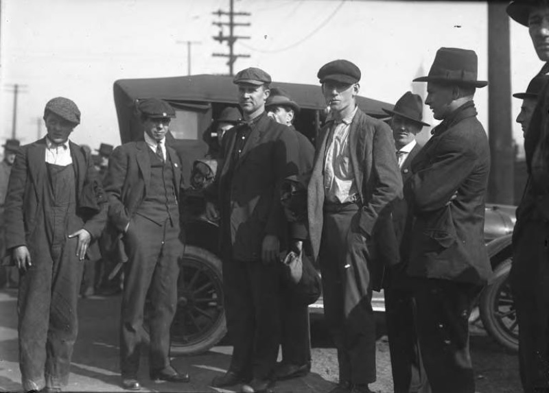 1920s men photographed in Seattle, Washington, wearing workwear such as overalls and work shirts with flat caps.