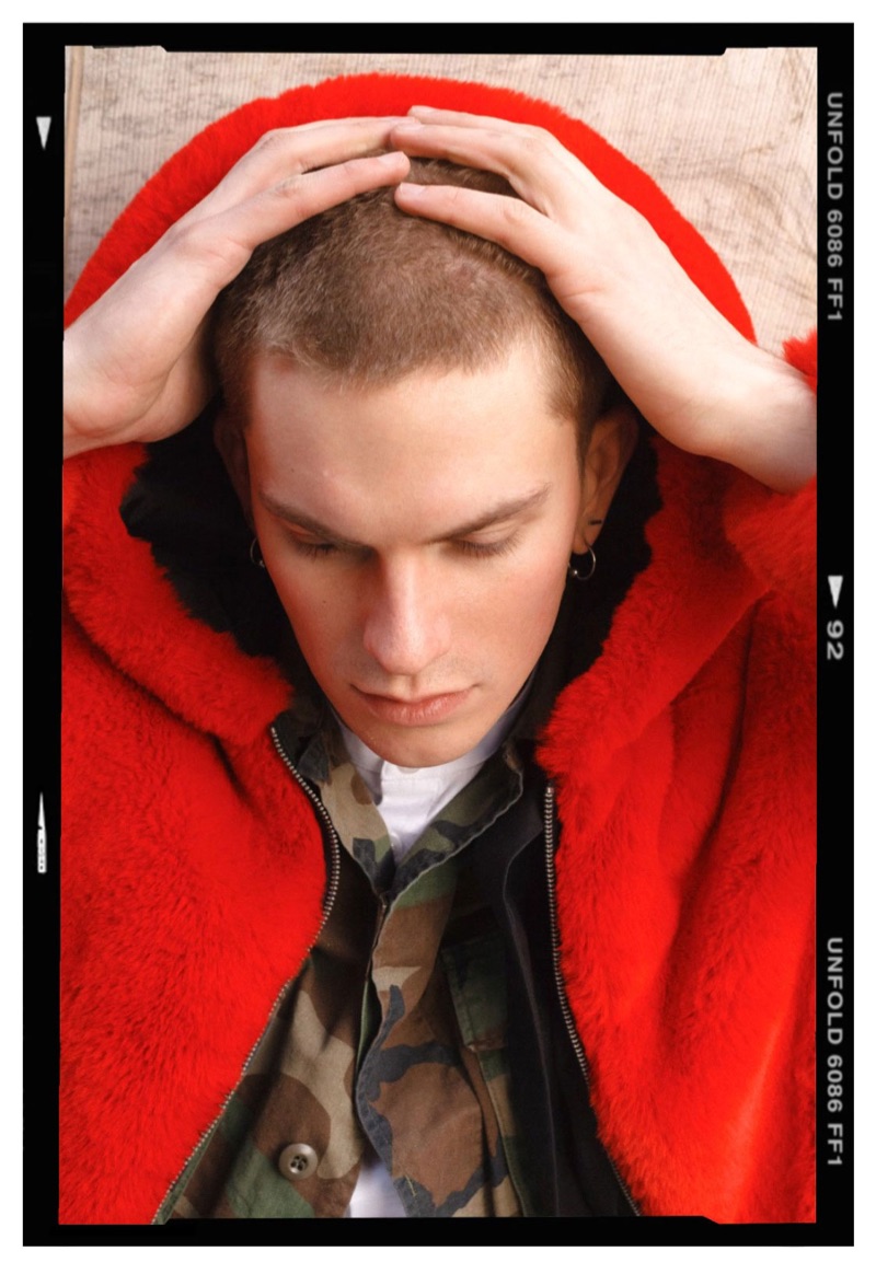 Model Alexander Morel sports a red fur jacket by PEACEMINUSONE with a Stüssy camouflage print jacket and Ralph Lauren shirt.