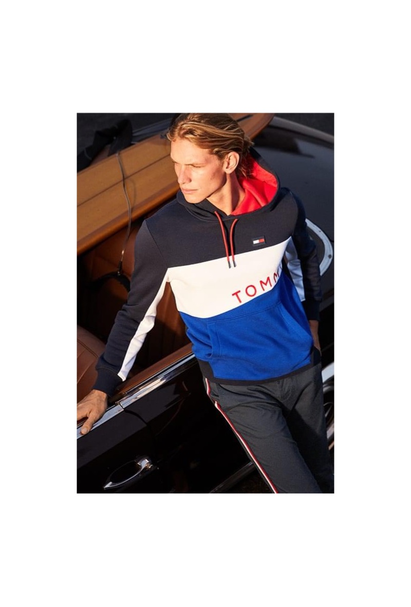 Going sporty, Hunter Bach wears a Tommy Hilfiger colorblocked graphic hoodie and stripe chinos.