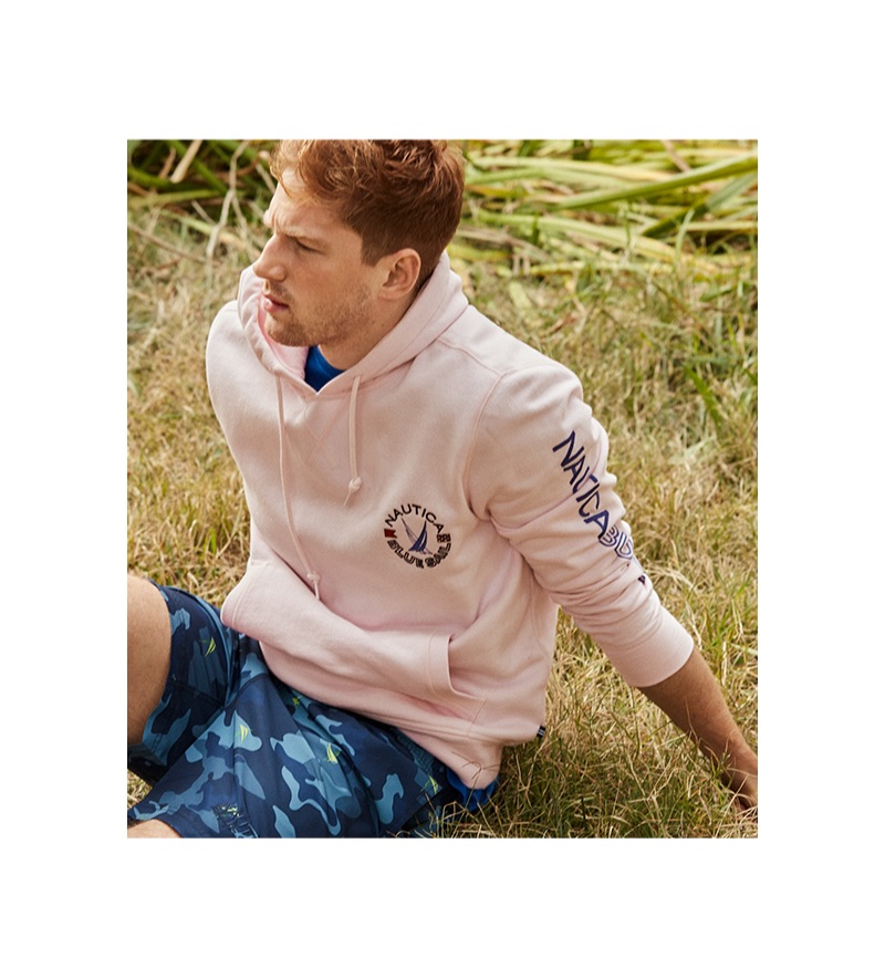 Relaxing, Race Imboden wears a Nautica Blue Sail hoodie and camouflage print swim trunks.