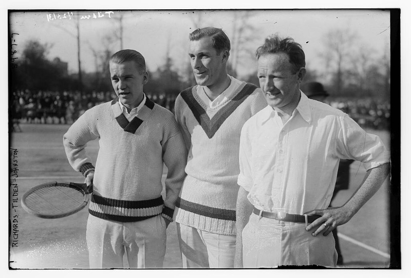 Tennis players Vincent Richards, Bill Tilden, and Bill Johnston pose for photos at a 1923 tennis match in v-neck sweaters and casual white shirts.