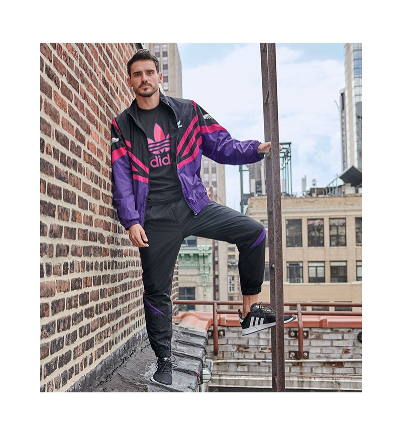 Channeling retro style, Arthur Kulkov rocks an adidas Originals sportive colorblocked track jacket, trackpants, and treifoil logo t-shirt.