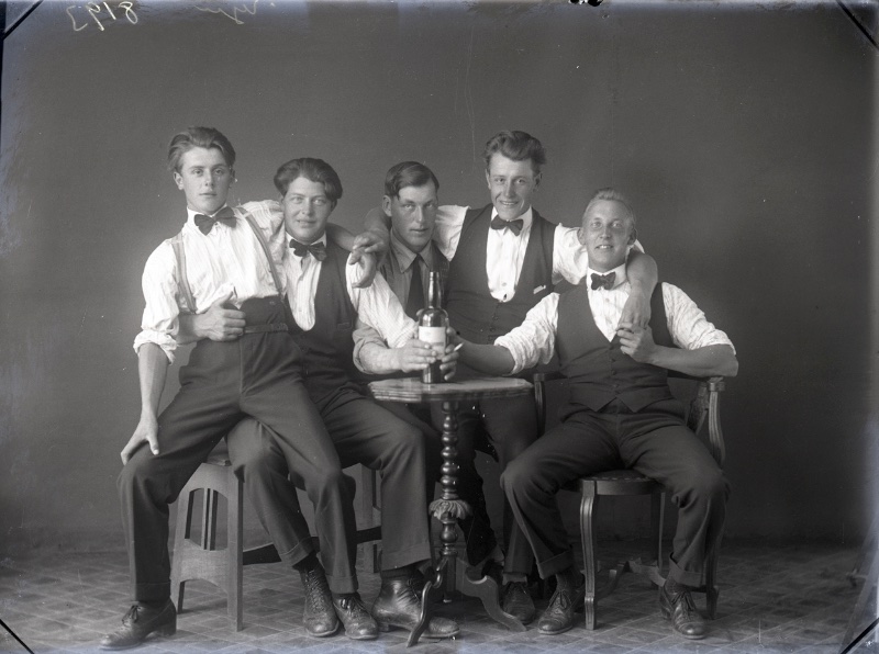 Showcasing 1920s classic style, friends pose in high-waist trousers with braces, bow ties, and waistcoats.