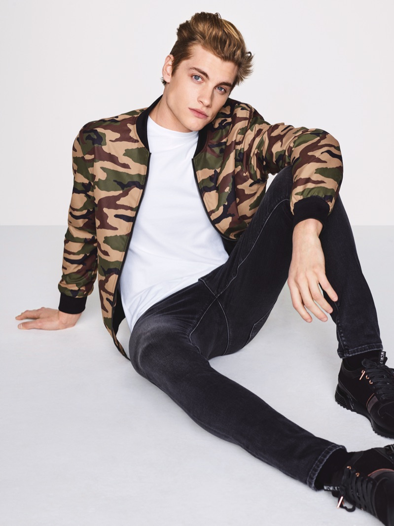 British model Rob Knighton wears a camouflage print bomber jacket with jeans by River Island.