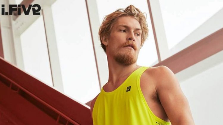 Ready for a workout, Harry Goodwins wears a yellow tank and running shorts by I.FIV5.