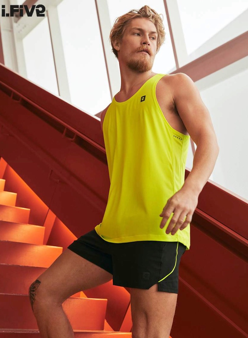 Ready for a workout, Harry Goodwins wears a yellow tank and running shorts by I.FIV5.