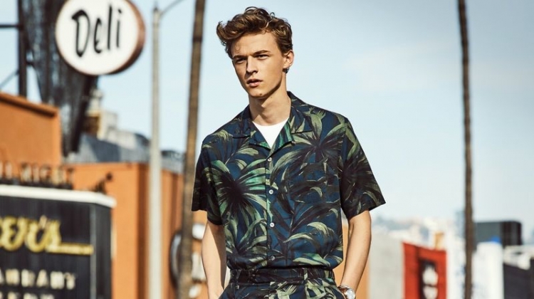 Making a tropical statement, Max Barczak dons a Todd Snyder olive palm print camp collar shirt and shorts.