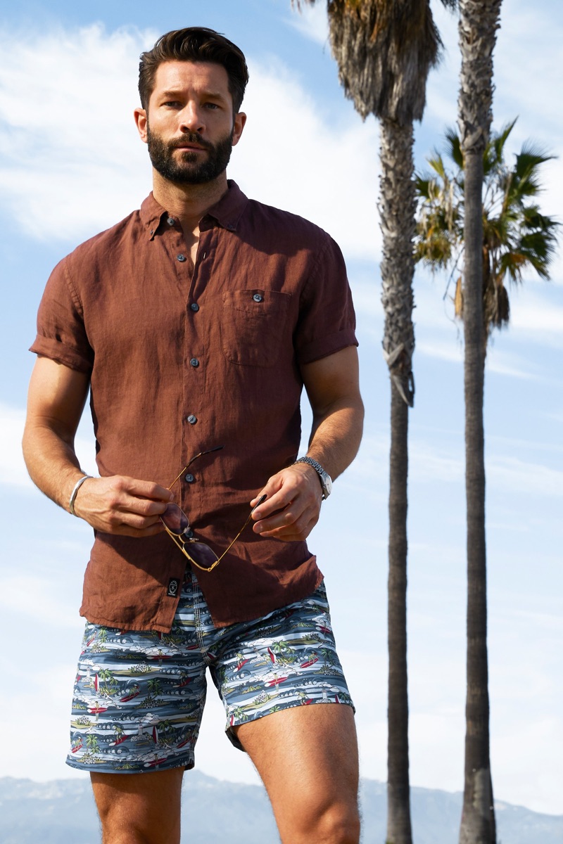 John Halls sports a brown Todd Snyder short-sleeve linen button-down shirt with Hartford Hawaiian surf print swim trunks.