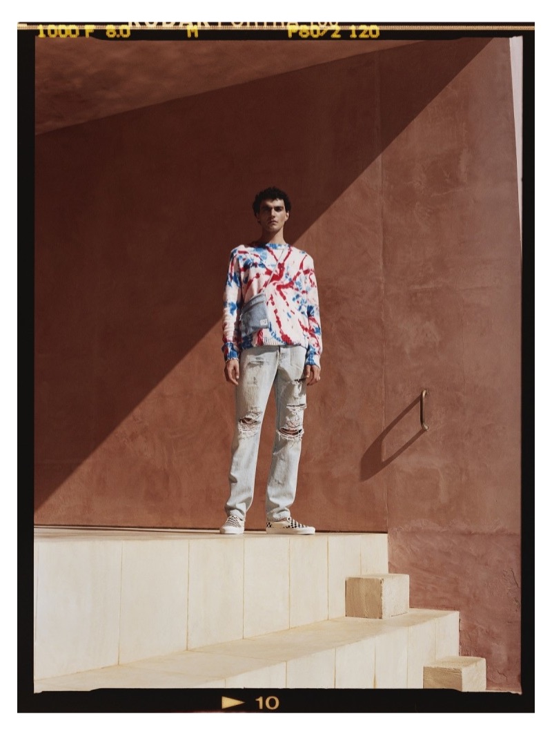 Embracing relaxed spring style, Dylan wears a tie-dye sweater by The Elder Statesman with AMIRI jeans, Vans sneakers, and an OrSlow denim messenger bag.