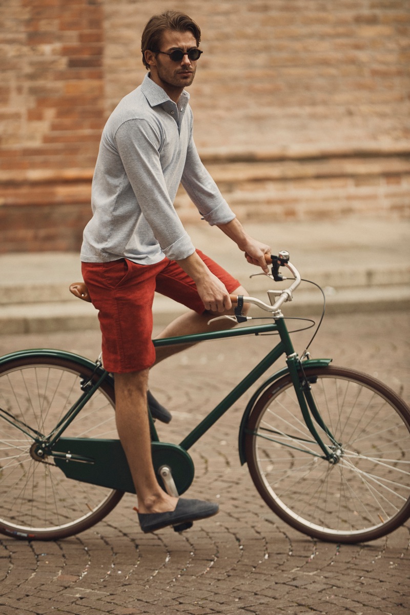 Riding a bike, Jacey Elthalion models Luca Faloni's Brera polo shirt.