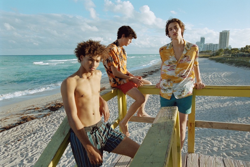 Models Miles Anderson, Claude Morgan, and Niks Gerbasevskis showcase swim shorts and Hawaiian print shirts from Pull & Bear.