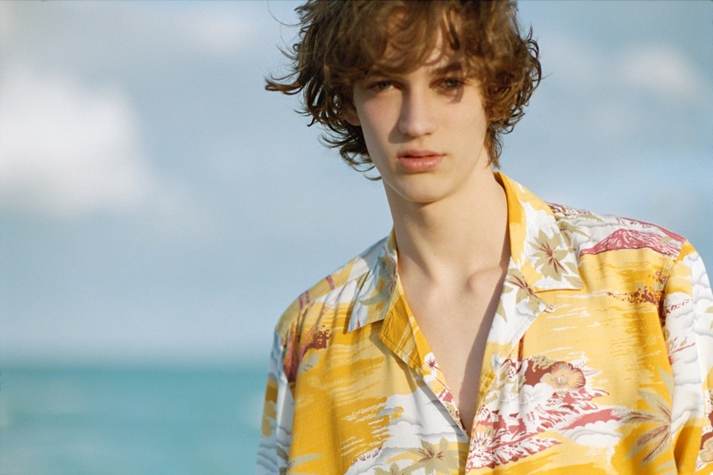 Taking to the beach, Niks Gerbasevskis wears a yellow Hawaiian shirt by Pull & Bear.