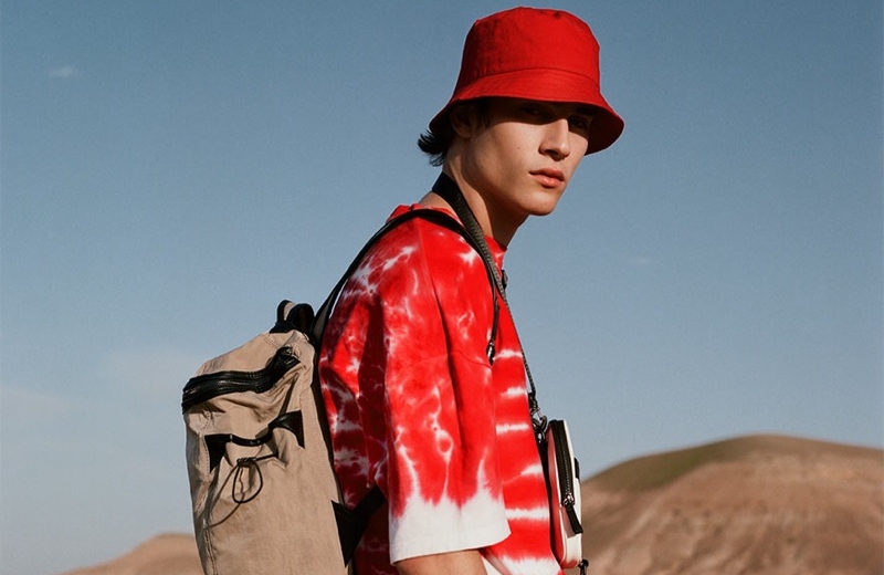 Liam Kelly Tackles Summer Style with Reserved Rocking red, Liam Kelly sports a tie-dye print t-shirt with a bucket hat and white pants by Reserved.
