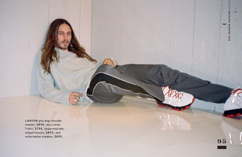Relaxing, Riley Hawk wears a Lanvin sweater, t-shirt, side-striped trousers, and sneakers.
