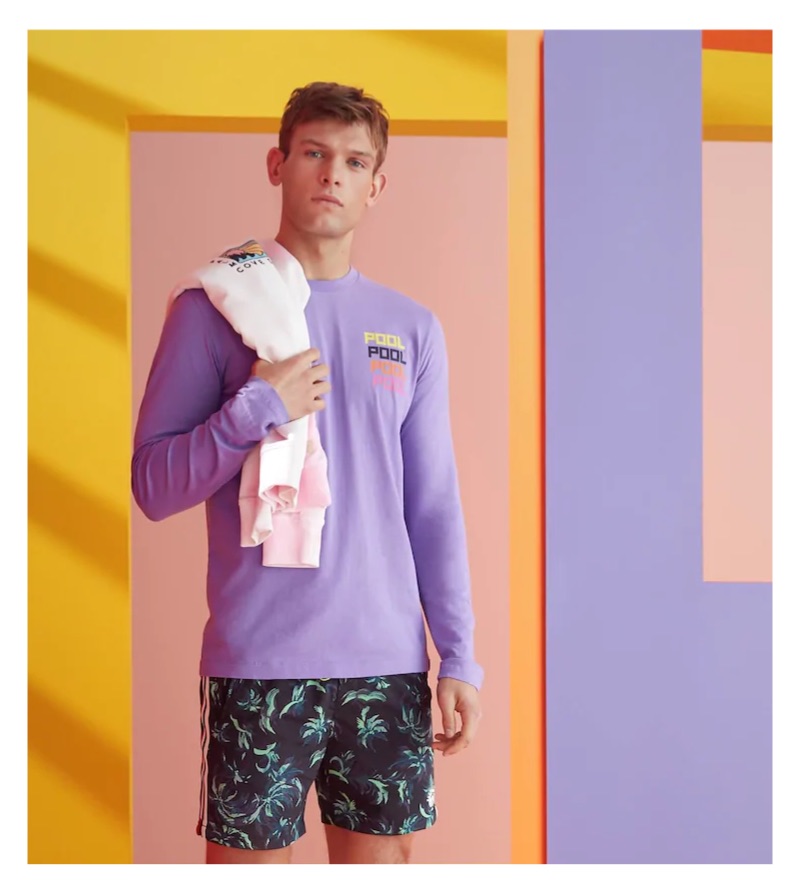 Elliott Reeder sports a purple print t-shirt and palm print swim shorts by Scotch & Soda.