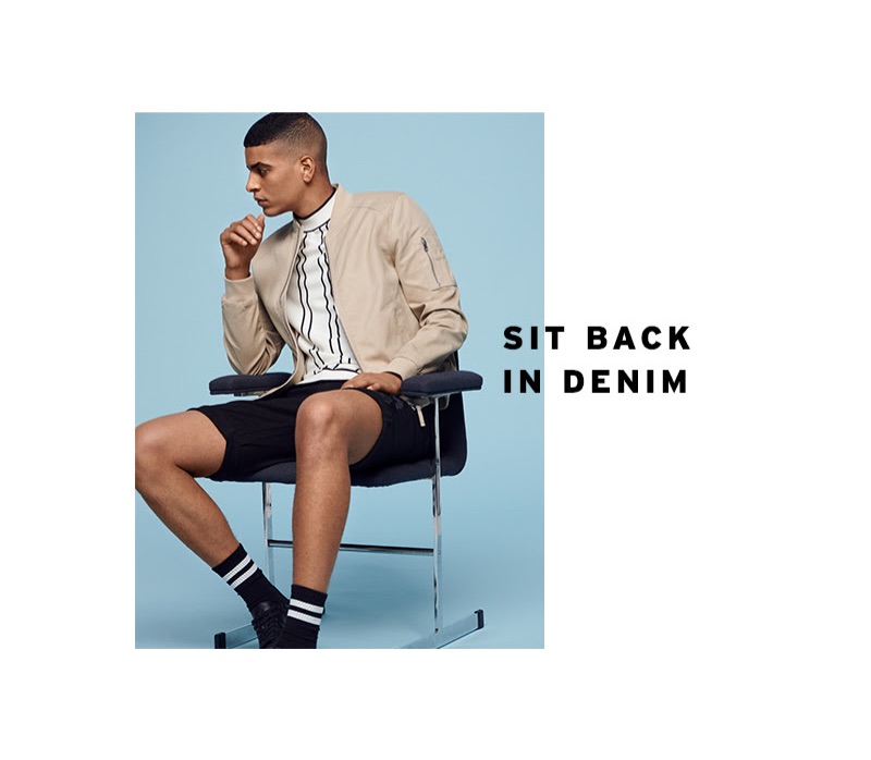 Connecting with Topman, Zakaria Khiare wears a stone-colored bomber jacket with a striped top and black denim shorts.