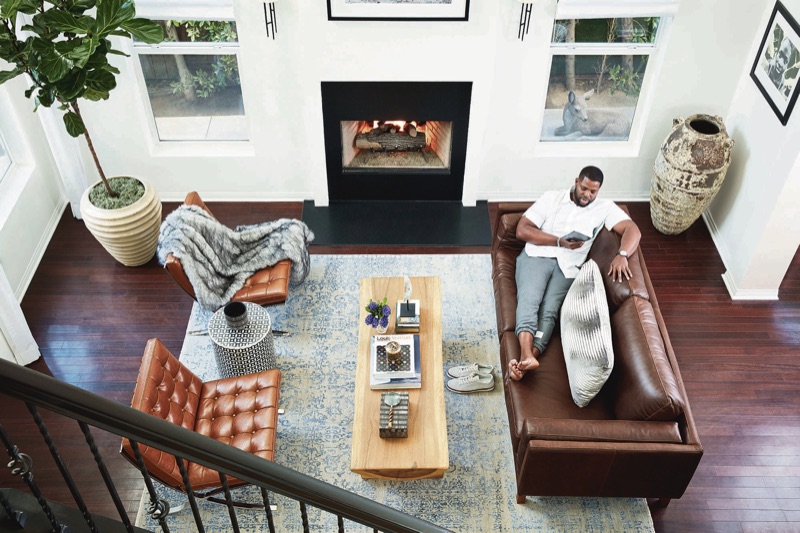 Relaxing, Winston Duke wears a Thom Browne shirt and joggers.