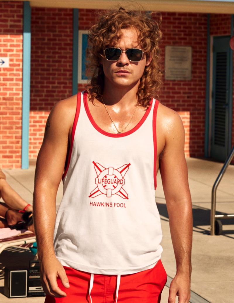 Dacre Montgomery wears a tank and red swim shorts from H&M's Stranger Things collaboration.