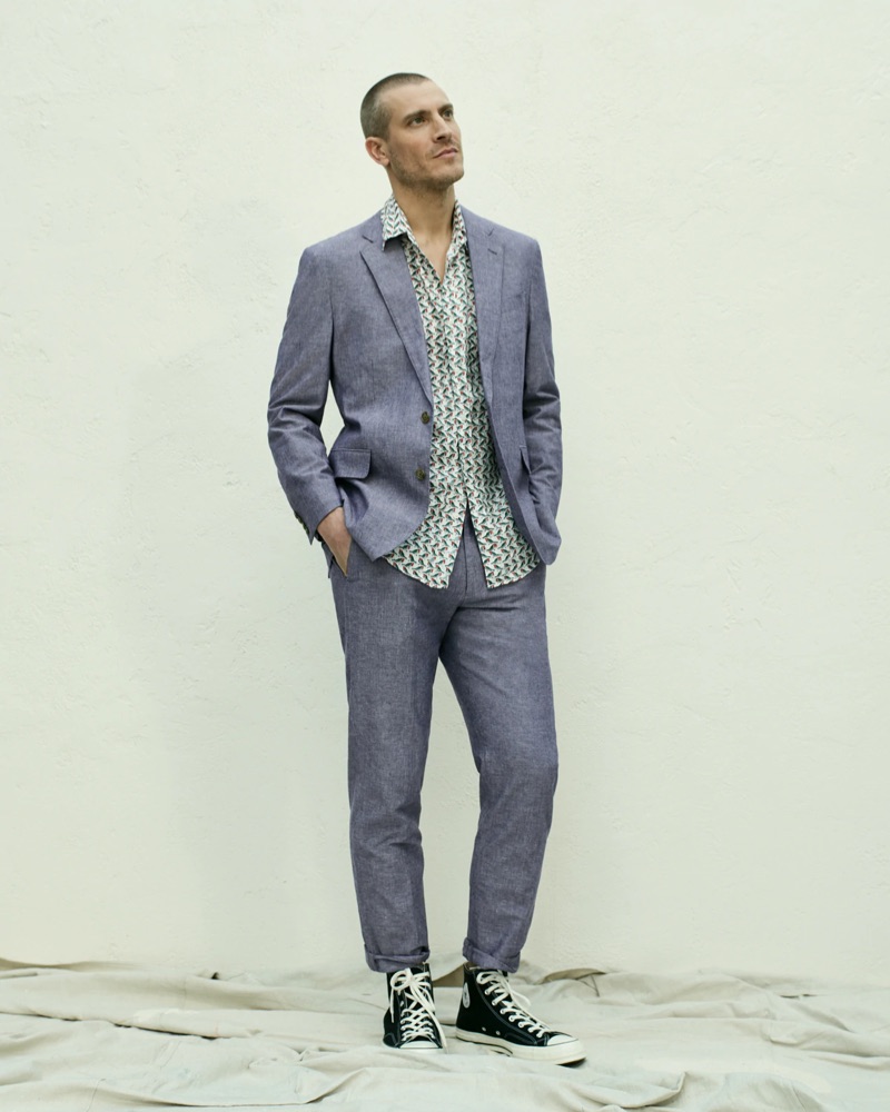 Mike Guenther wears a J.Crew Ludlow slim-fit unstructured suit jacket in cotton-linen with matching suit pants. He also dons a J.Crew short-sleeve linen shirt with a baby birds print and Converse Chuck Taylor All Star '70 high-top sneakers.