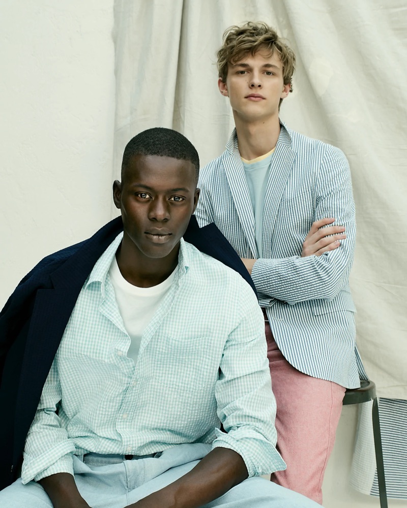 Left: Alpha Dia wears a blue J.Crew seersucker shirt, essential crewneck t-shirt, indigo chambray double-pleated pants, and a Ludlow slim-fit unstructured blazer in stretch seersucker. Right: Max Barczak sports a blue J.Crew Ludlow slim-fit unstructured blazer in seersucker with two essential crewneck t-shirts. The model also wears the brand's 770 straight-fit chino pants in stretch chambray.