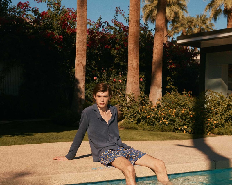 Relaxing poolside, Efraim Schröder dons an Orlebar Brown shirt and Frescobol Carioca swim shorts.