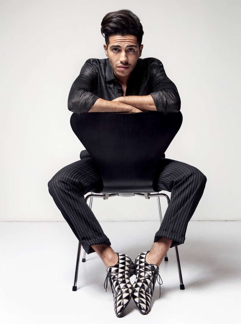 Actor Mena Massoud wears a glitter shirt, pinstripe trousers, and printed dress shoes by Saint Laurent.