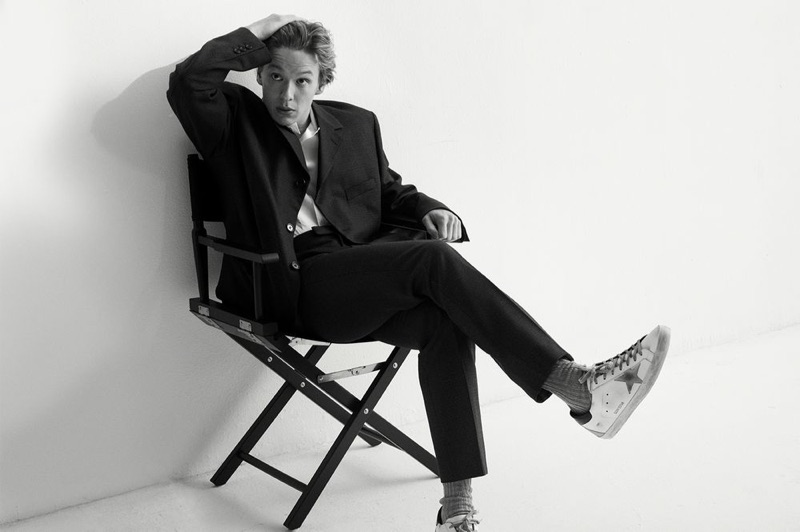 Taking to the studio, Freddie Wise wears a Raf Simons suit jacket and trousers with a Helmut Lang camp-collar shirt. The actor also sports Brunello Cucinelli socks and Golden Goose Superstar sneakers.