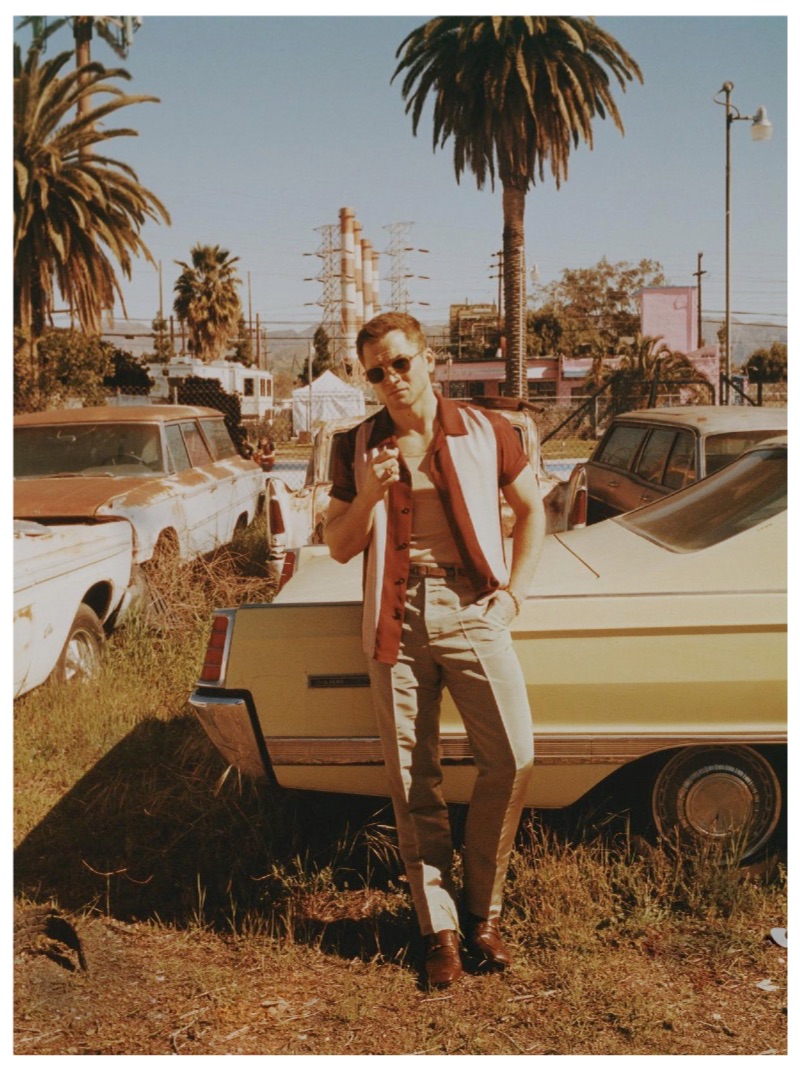 Taron Egerton dons a Sandro shirt, Tom Ford t-shirt, Dolce & Gabbana pants, Gucci shoes, and Billy Reid sunglasses.