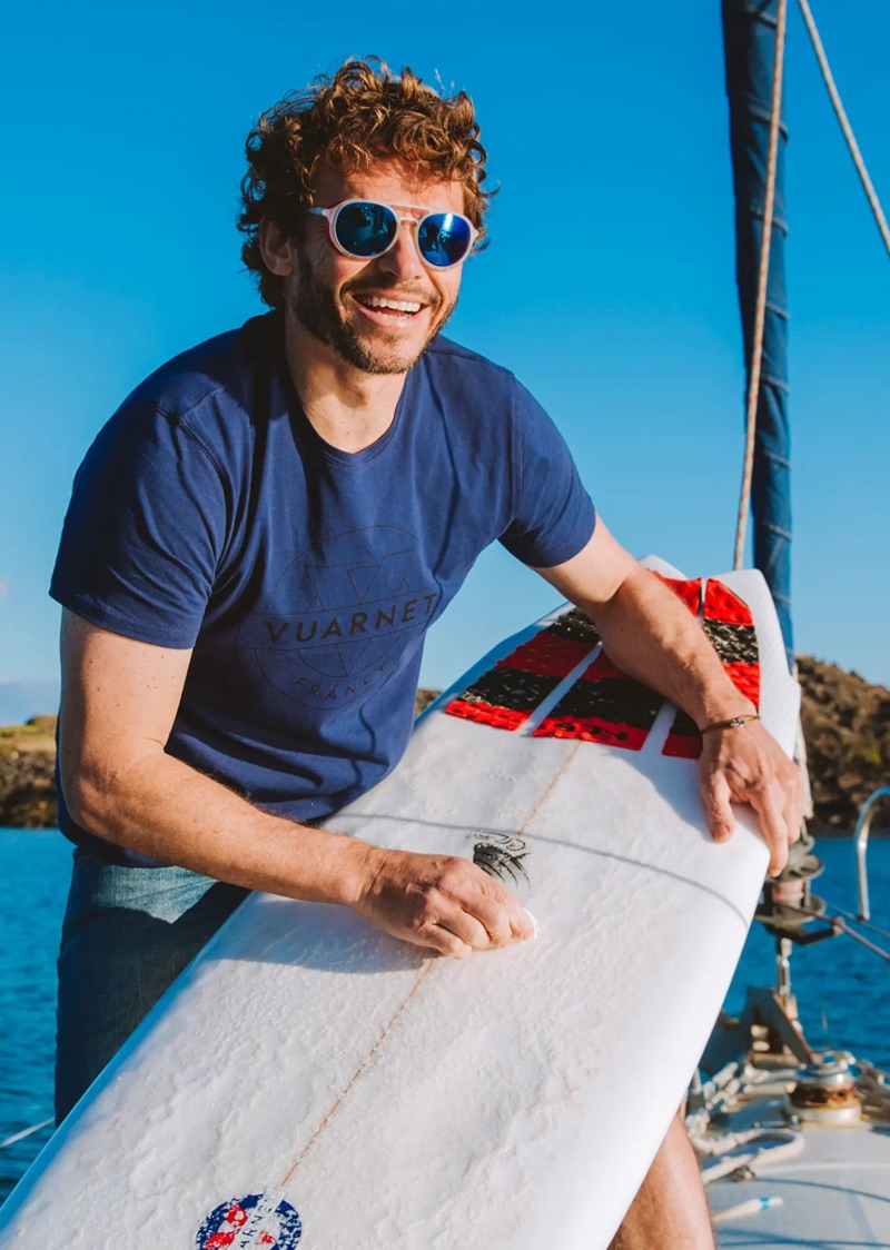 Sporting Vuarnet sunglasses, Arnaud Binard waxes his surfboard.