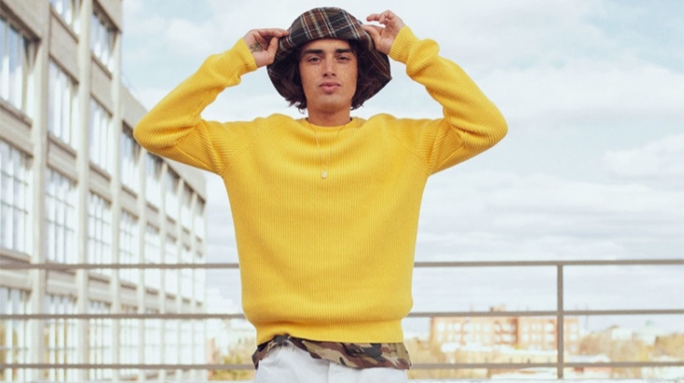 Naleye Dolmans sports a yellow ribbed sweater with a camouflage t-shirt, plaid bucket hat, and pants from Zara.