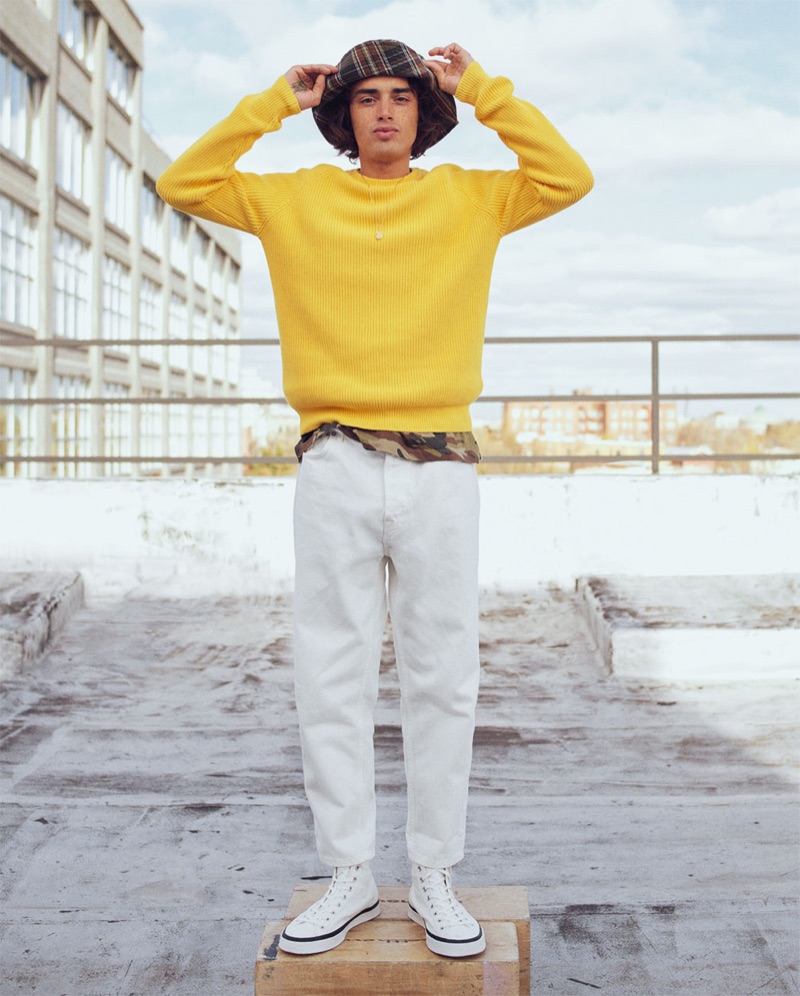 Naleye Dolmans sports a yellow ribbed sweater with a camouflage t-shirt, plaid bucket hat, and pants from Zara.