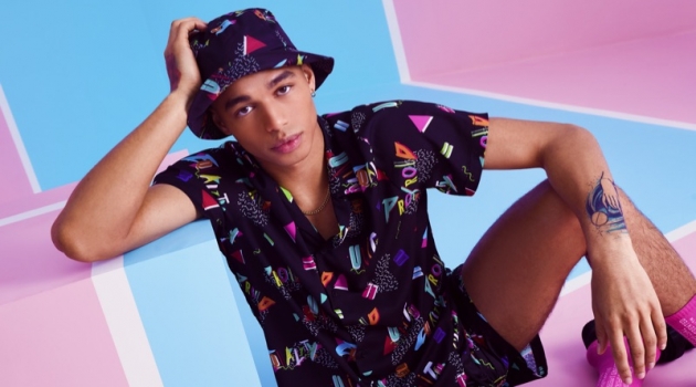 Shae Pulver wears a matching shirt, shorts, and bucket hat from boohooMAN's Pride 2019 collection.