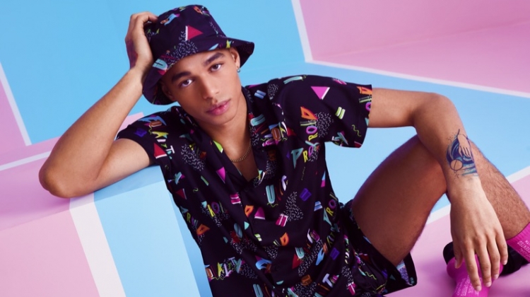 Shae Pulver wears a matching shirt, shorts, and bucket hat from boohooMAN's Pride 2019 collection.