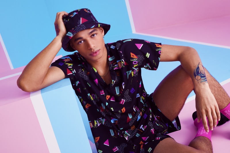 Shae Pulver wears a matching shirt, shorts, and bucket hat from boohooMAN's Pride 2019 collection.