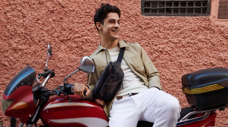 All smiles, Cyrus Amini wears Banana Republic's Core Temp coach's jacket $149, chinos $98, suede loafers $148, and a camouflage print belt bag $59.50.