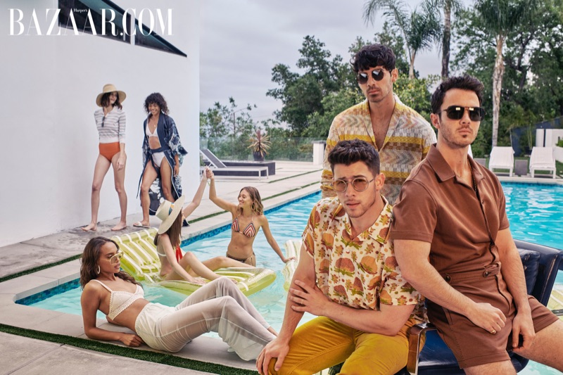 Relaxing poolside, Nick Jonas wears a Bode shirt, Missoni pants, and Giorgio Armani sunglasses. Joe Jonas dons a Missoni cardigan and pants with Etro green loafers and (SALT) sunglasses. Kevin Jonas sports a Mr. Turk jumpsuit and M2M sunglasses with a David Yurman necklace and ring.