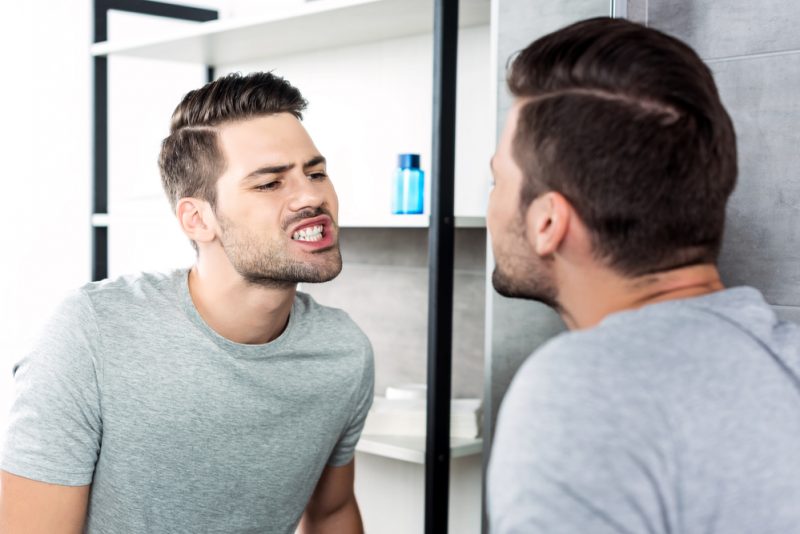 Man with White Teeth Looking in Mirror