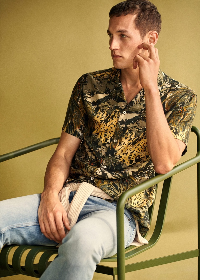 Sitting for a photo, Rutger Schoone dons a printed shirt with a textured knit and light wash jeans by Mango.