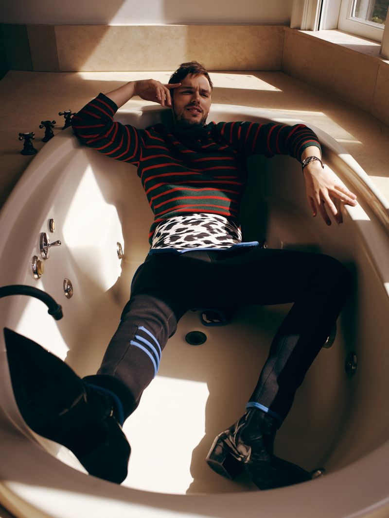 Posing in a bathtub, Nicholas Hoult sports a quirky look by Calvin Klein 205W39NYC.