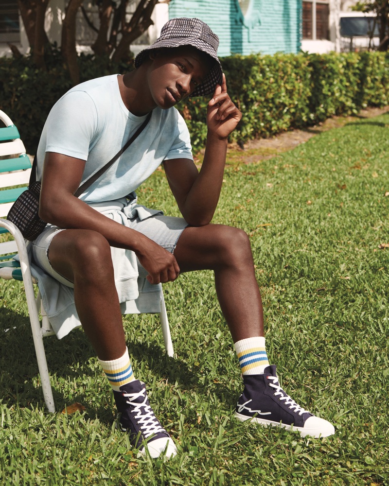 Connecting with River Island, David Agobdji sports a summer look, complete with a plaid bag and bucket hat.