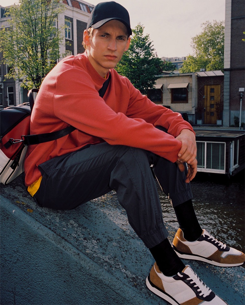 Giel Dils wears a red sweatshirt, poplin pants, sneakers, and accessories from Zara.