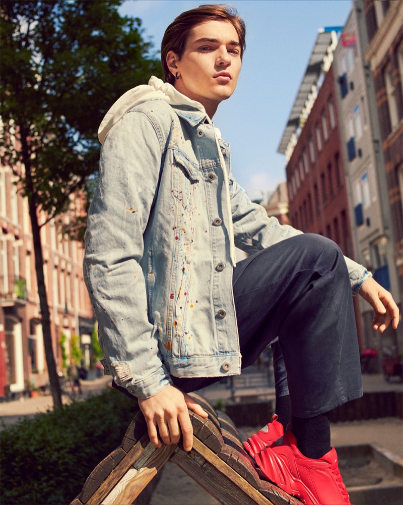 Felix Prabitz sports a denim jacket with a hooded sweatshirt, jumpsuit, and sneakers by Zara.