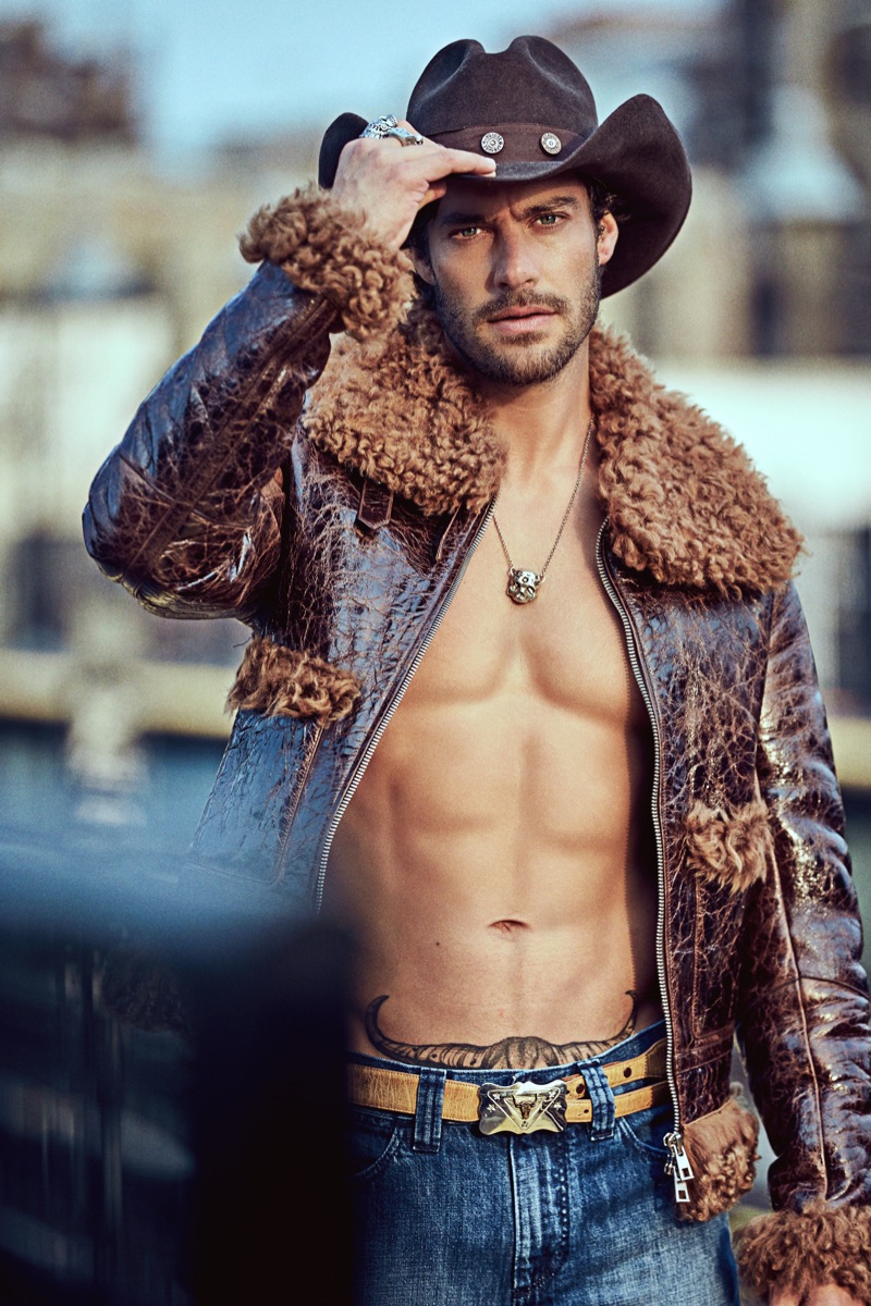 Gonçalo wears hat and belt Space Cowboy, necklace and rings Britt Bolton Jewelry, jacket and jeans Michael Kors Collection.